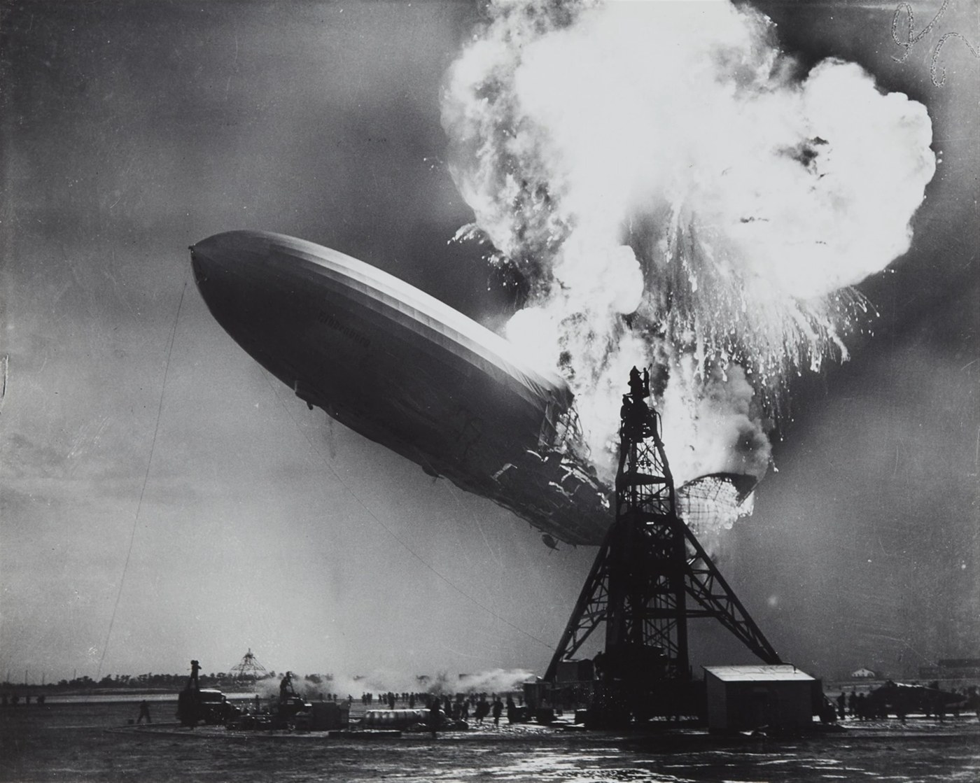 Original black-and-white photograph of the Hindenburg airship on fire beside its mooring mast